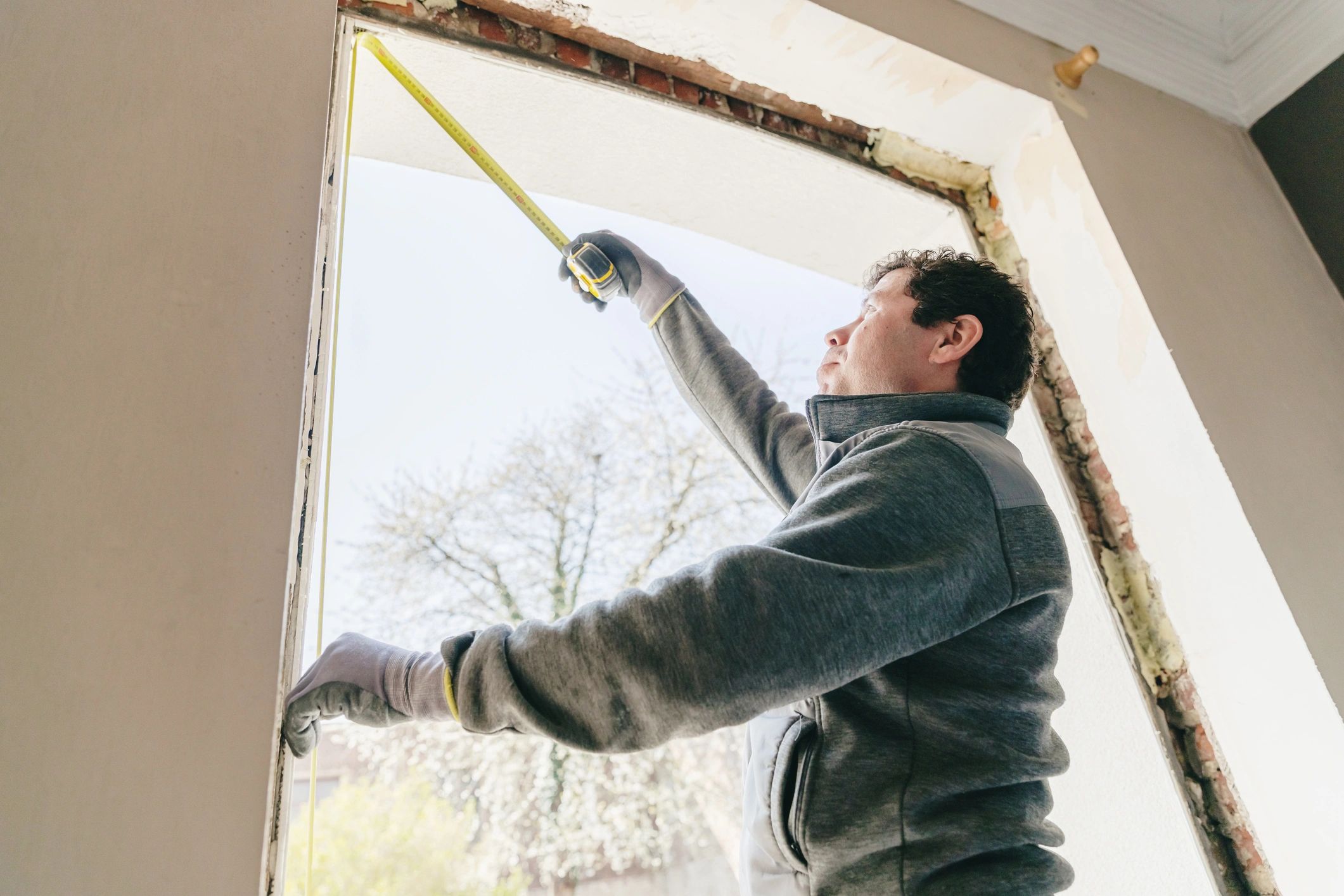 Installer measuring a window opening during renovation